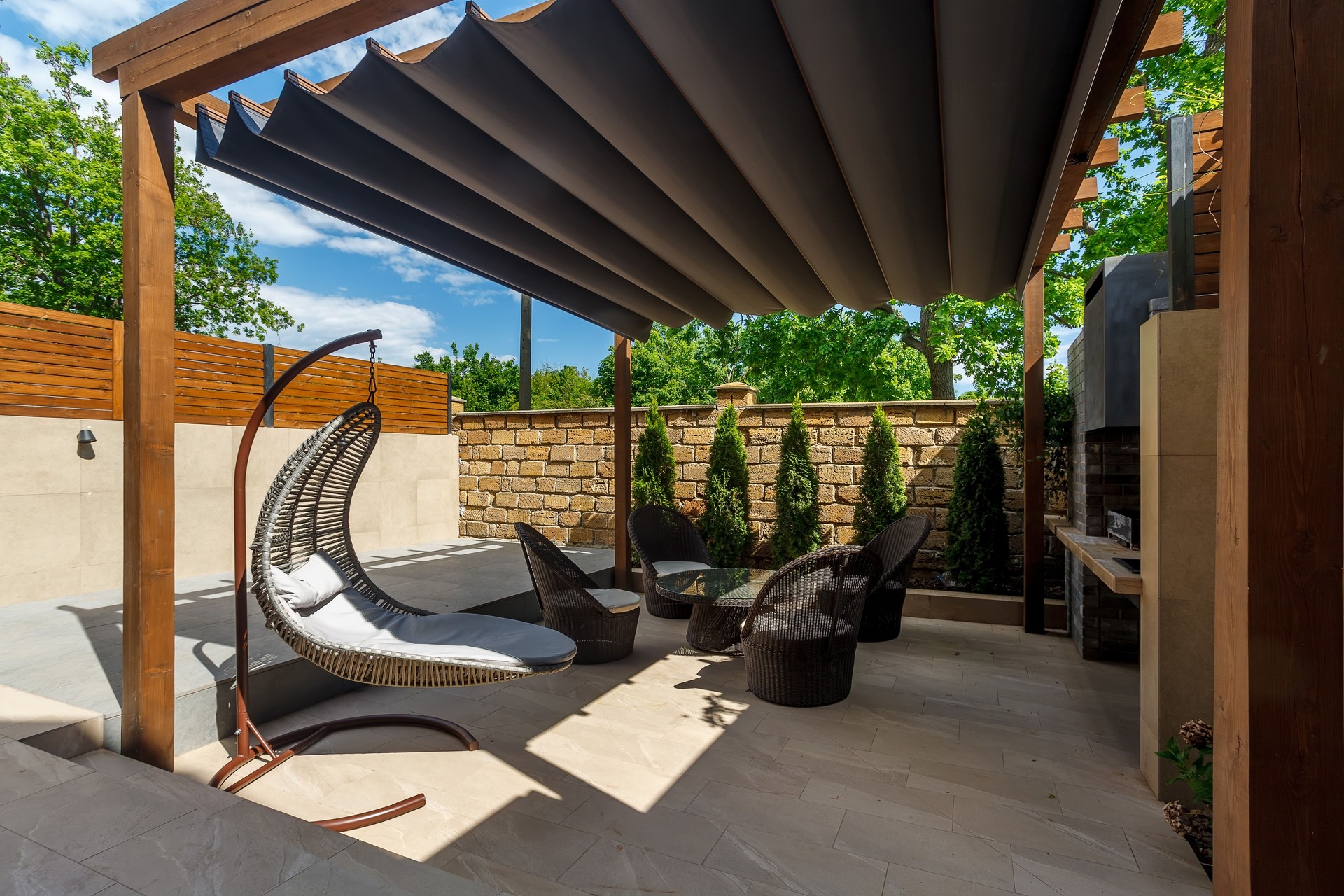 Backyard outdoor bbq zone with pergola, fireplace and hanging chair. Summer party place